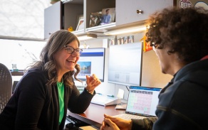 Advisor is meeting in an office with a student. 