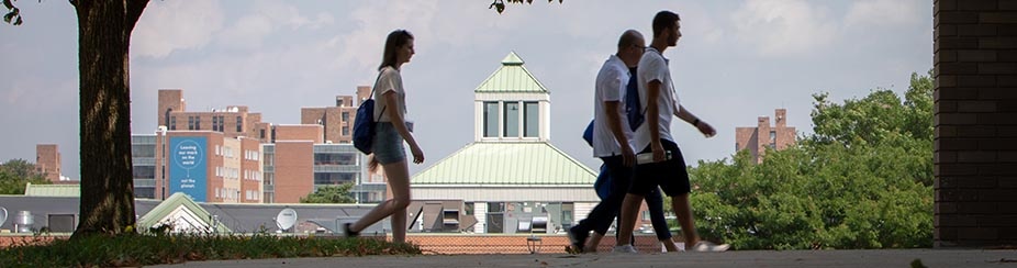 Three students walking on North Campus with the UB Commons buildings in the background.