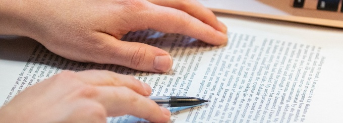 Close-up of a student's hands as they are reviewing a written paper. 
